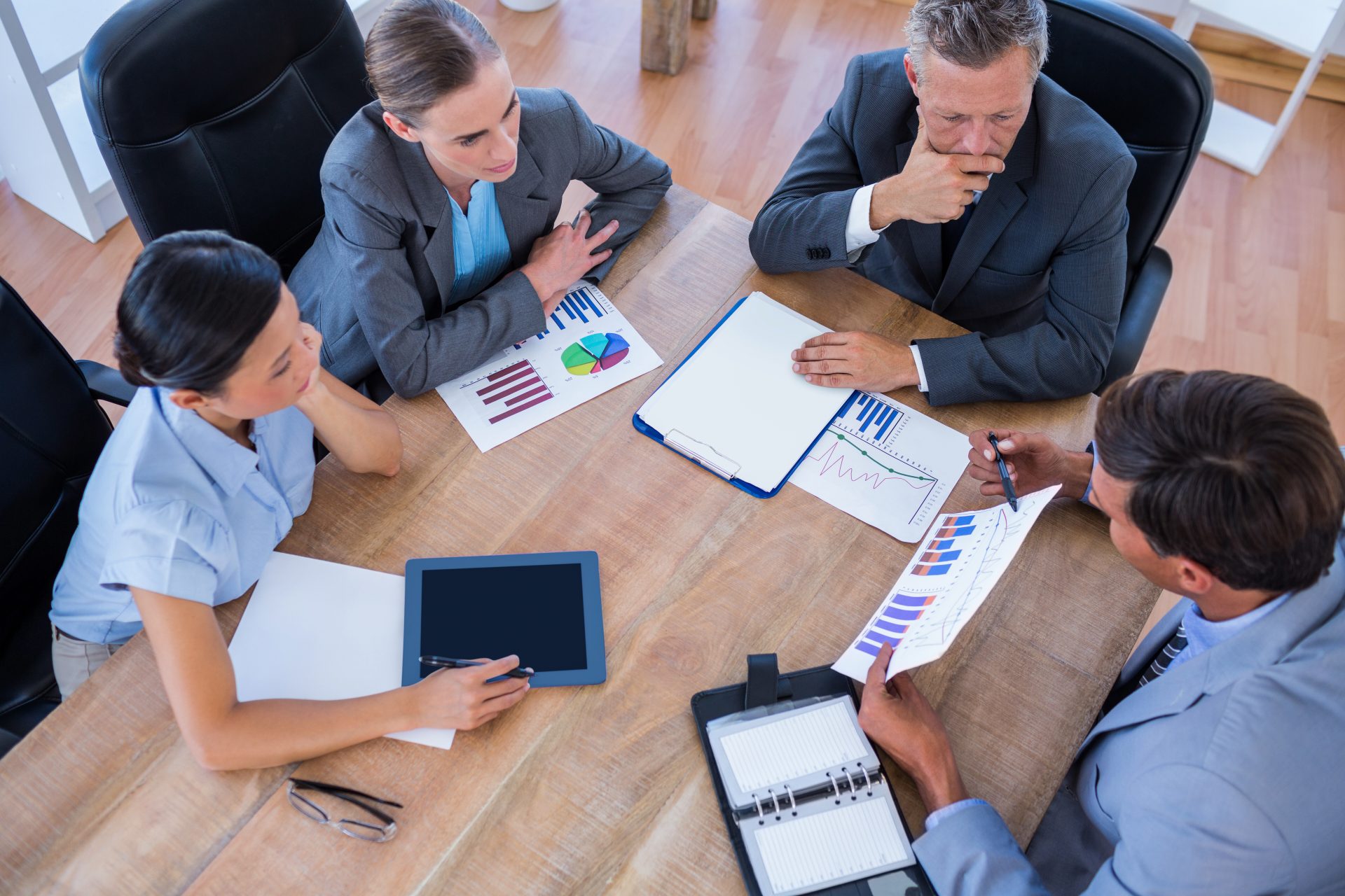 Business team analyzing strategy and financial graphs during a meeting, focusing on collaboration and productivity in entrepreneurship.
